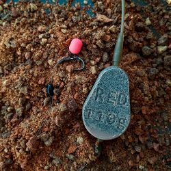 Red Sinker Inline nehezék 110 grammos változatban, sáros terepen fotózva. Red Sinker Környezetbarát horgász súlyok Inline 110g sáros környezetben