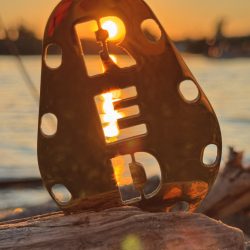 A Red Sinker ikonikus logója a naplemente fényében – erő és stílus egyben. Red Sinker logóval ellátott horgász súly naplementében, faágon